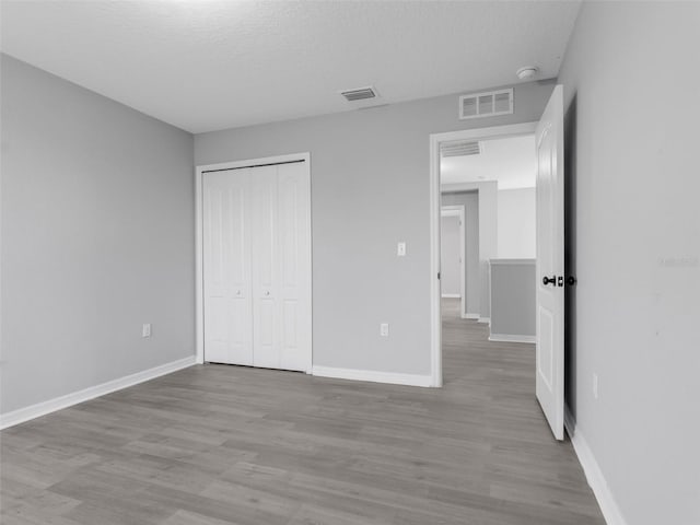 unfurnished bedroom with visible vents, light wood-style flooring, and baseboards