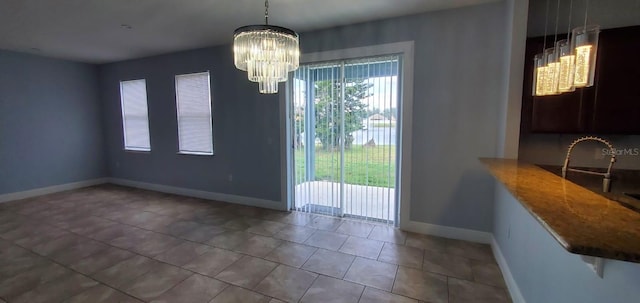 unfurnished dining area with an inviting chandelier, tile patterned flooring, and baseboards