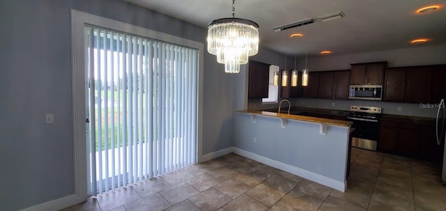 kitchen with a breakfast bar area, a peninsula, a healthy amount of sunlight, hanging light fixtures, and appliances with stainless steel finishes