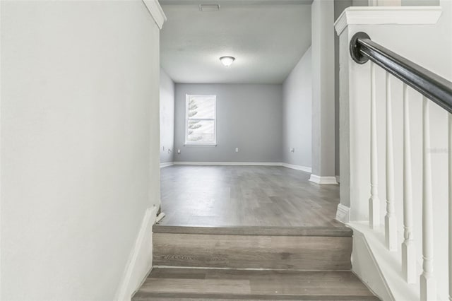 stairway featuring a textured ceiling, baseboards, and wood finished floors