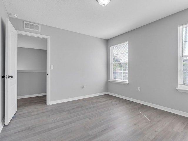 unfurnished bedroom featuring baseboards, visible vents, and light wood finished floors