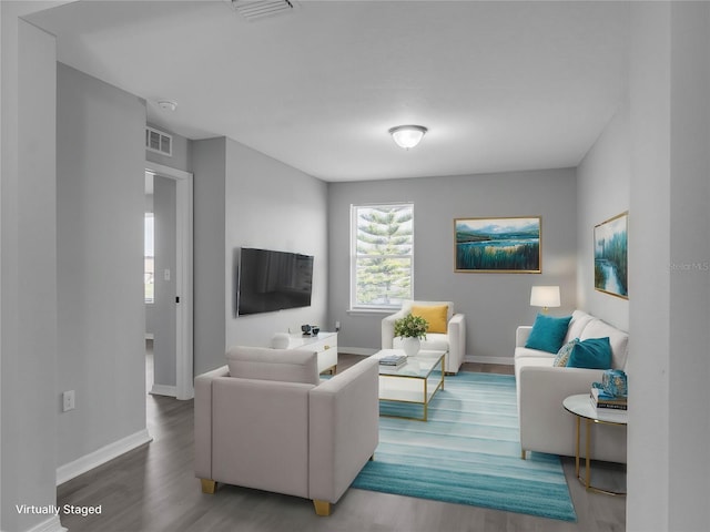 living room with wood finished floors, visible vents, and baseboards