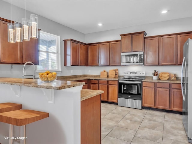 kitchen with brown cabinetry, a breakfast bar area, decorative light fixtures, a peninsula, and stainless steel appliances