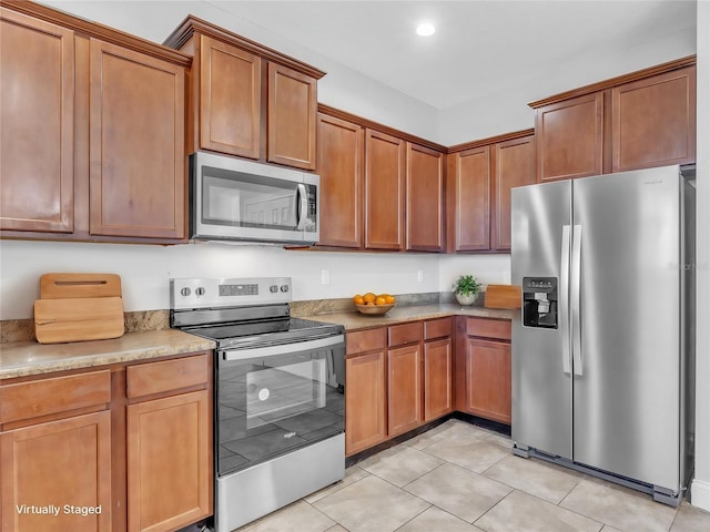 kitchen featuring light tile patterned floors, appliances with stainless steel finishes, brown cabinetry, and recessed lighting