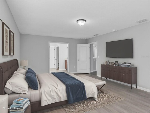 bedroom with visible vents, baseboards, and wood finished floors