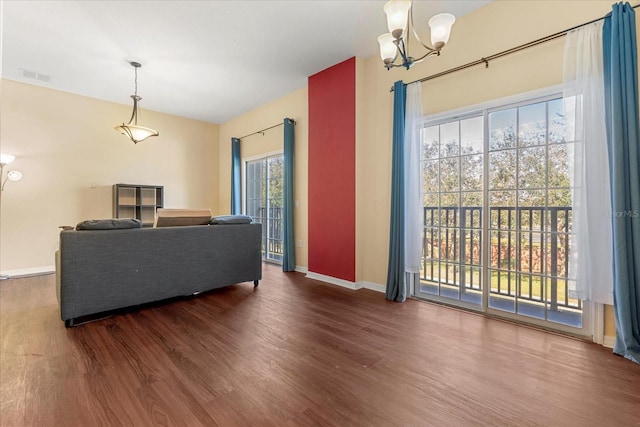 living room with a notable chandelier, dark wood-type flooring, and a wealth of natural light