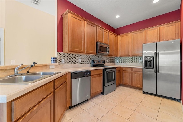 kitchen with appliances with stainless steel finishes, decorative backsplash, sink, and light tile patterned floors