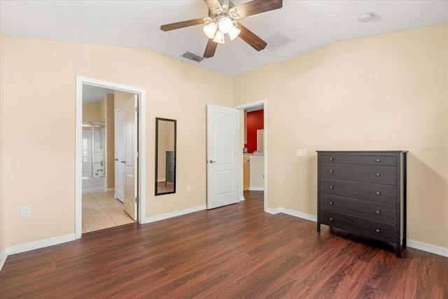 unfurnished bedroom featuring dark wood-type flooring, ensuite bath, lofted ceiling, and ceiling fan