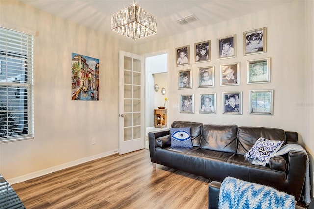 living room with french doors, a notable chandelier, and wood-type flooring