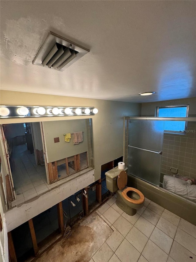 bathroom with tile patterned flooring and shower / bath combination with glass door