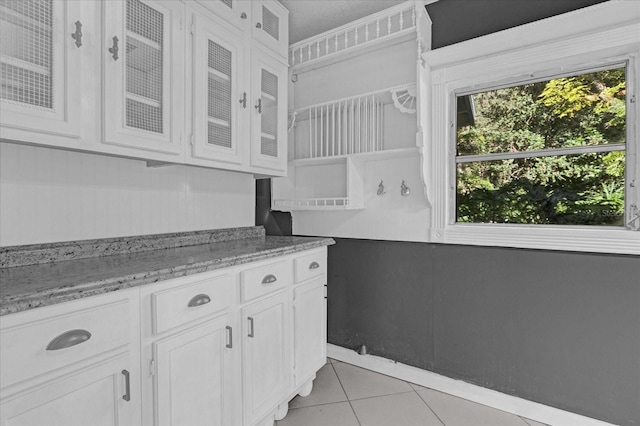 kitchen featuring light stone countertops, white cabinets, and light tile patterned flooring