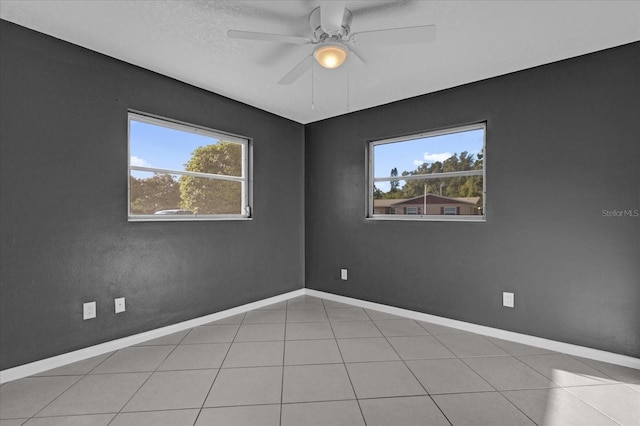 spare room featuring light tile patterned floors, ceiling fan, and a healthy amount of sunlight