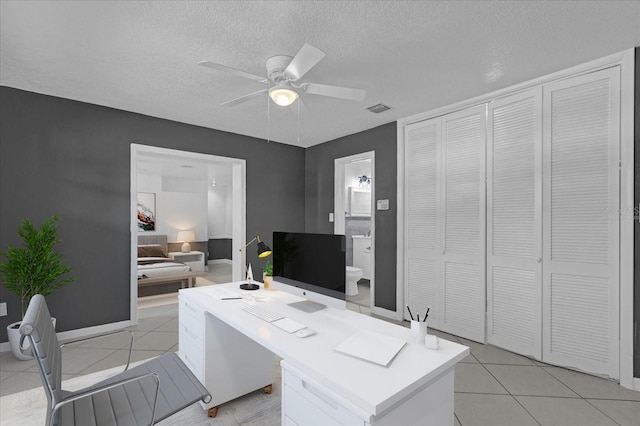 home office featuring ceiling fan, light tile patterned floors, and a textured ceiling