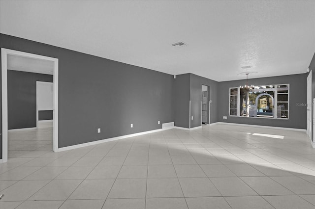 unfurnished living room with light tile patterned floors, a textured ceiling, and a chandelier