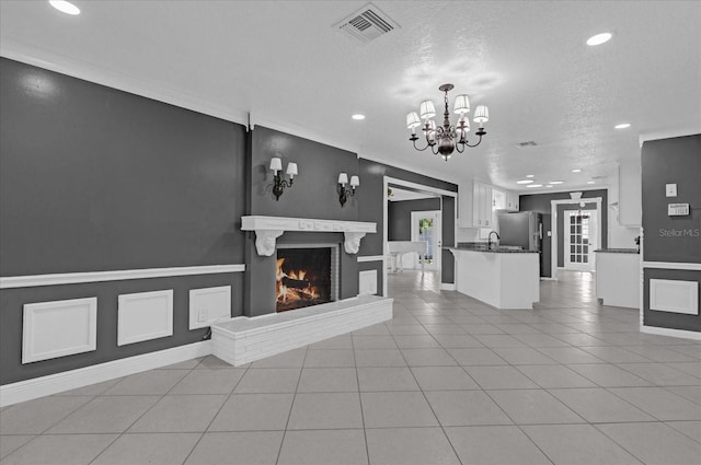 tiled living room featuring a chandelier, sink, a textured ceiling, and a brick fireplace