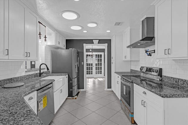 kitchen with white cabinets, wall chimney exhaust hood, a textured ceiling, and appliances with stainless steel finishes