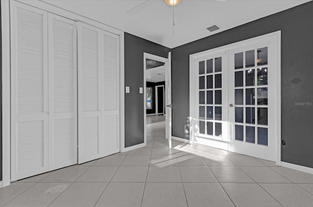 unfurnished bedroom featuring ceiling fan, light tile patterned flooring, a closet, and french doors