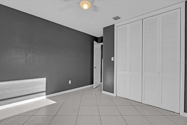 unfurnished bedroom featuring ceiling fan, light tile patterned flooring, and a closet