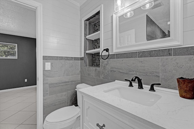 bathroom featuring vanity, a textured ceiling, tile walls, tile patterned flooring, and toilet