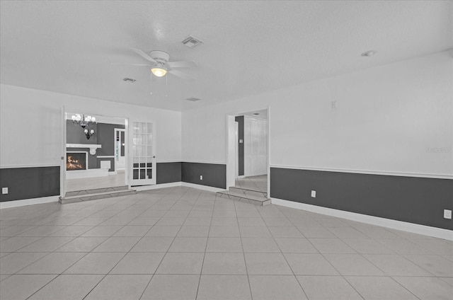 unfurnished living room with ceiling fan, light tile patterned flooring, and a textured ceiling