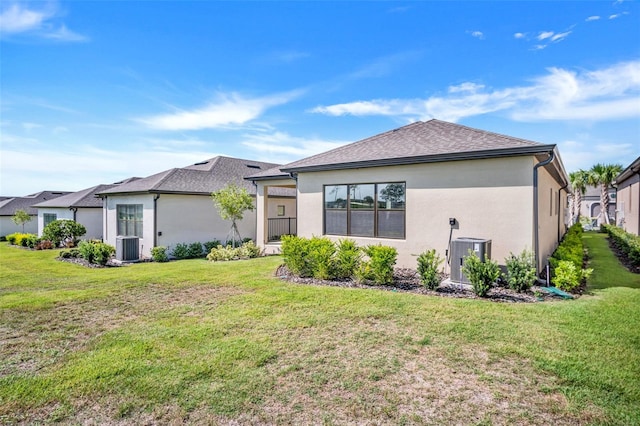 rear view of property with central air condition unit and a lawn