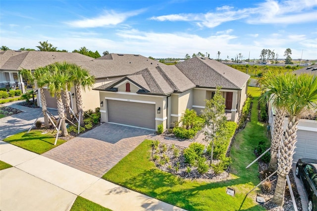 view of front of house with a front yard, roof with shingles, stucco siding, decorative driveway, and a garage