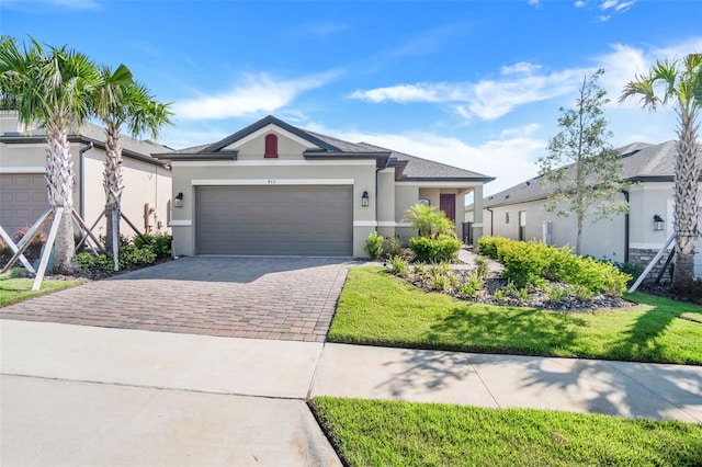 view of front of house featuring a front yard, decorative driveway, a garage, and stucco siding