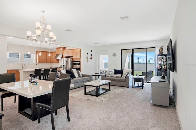 living area with light carpet, visible vents, plenty of natural light, and an inviting chandelier