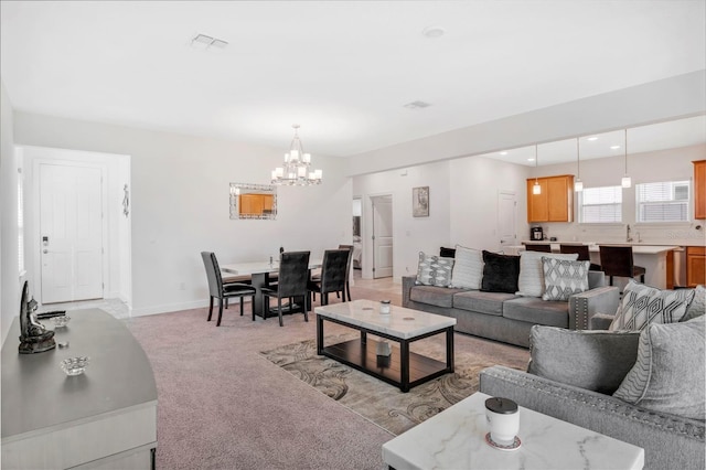 living room featuring baseboards, visible vents, light carpet, and an inviting chandelier