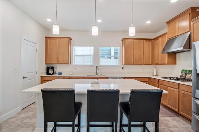 kitchen with a kitchen island, a breakfast bar area, exhaust hood, gas cooktop, and a sink