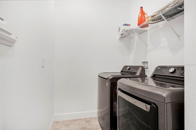 laundry room with laundry area, light tile patterned floors, baseboards, and independent washer and dryer