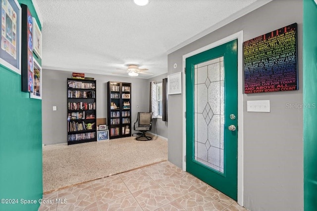 carpeted foyer with a textured ceiling and ceiling fan