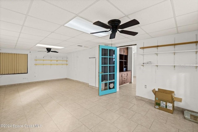 unfurnished room featuring a paneled ceiling, light tile patterned floors, and ceiling fan