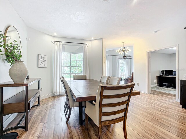 dining room featuring light wood-type flooring, an inviting chandelier, and a textured ceiling