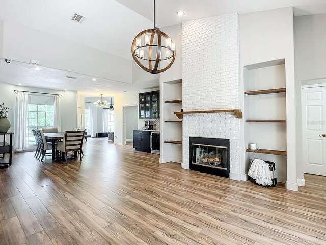 living room with a towering ceiling, a fireplace, hardwood / wood-style flooring, and an inviting chandelier