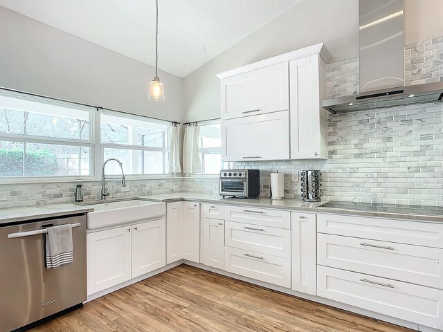 kitchen featuring dishwasher, wall chimney range hood, vaulted ceiling, and backsplash