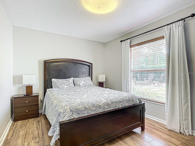 bedroom featuring light hardwood / wood-style floors and a textured ceiling