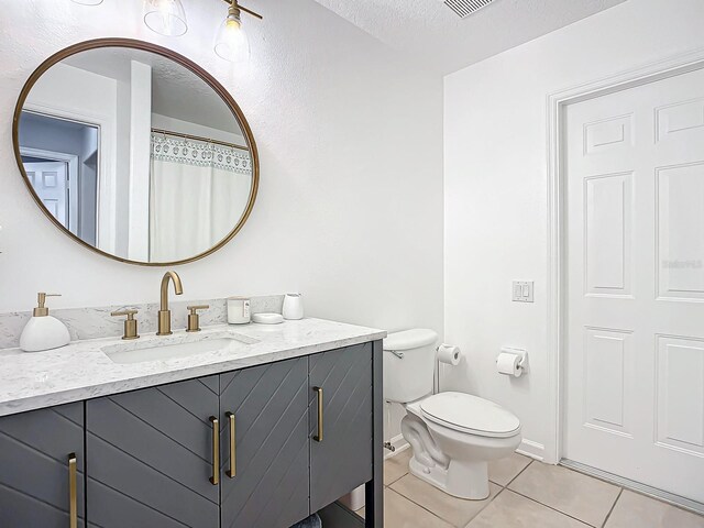 bathroom with toilet, vanity, a textured ceiling, and tile patterned floors