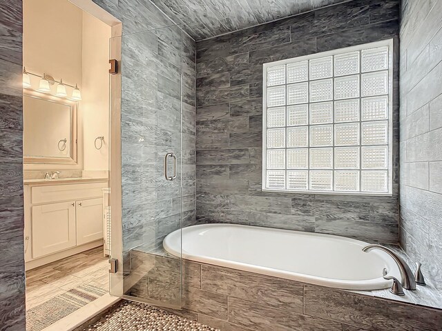 bathroom with tile walls, vanity, shower with separate bathtub, and hardwood / wood-style floors