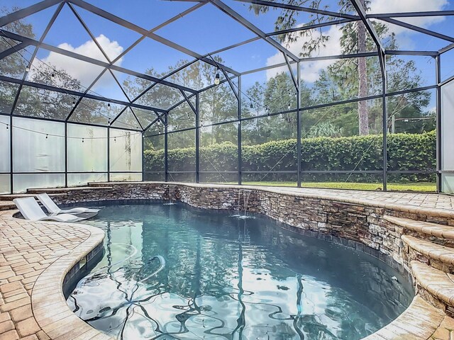 view of pool featuring a patio, glass enclosure, and pool water feature