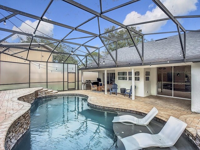 view of pool with a patio, outdoor lounge area, glass enclosure, and pool water feature