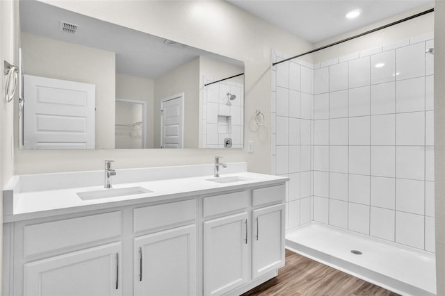 bathroom with a tile shower, vanity, and hardwood / wood-style flooring