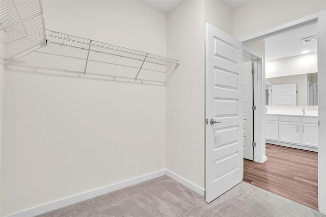 walk in closet featuring light carpet and sink