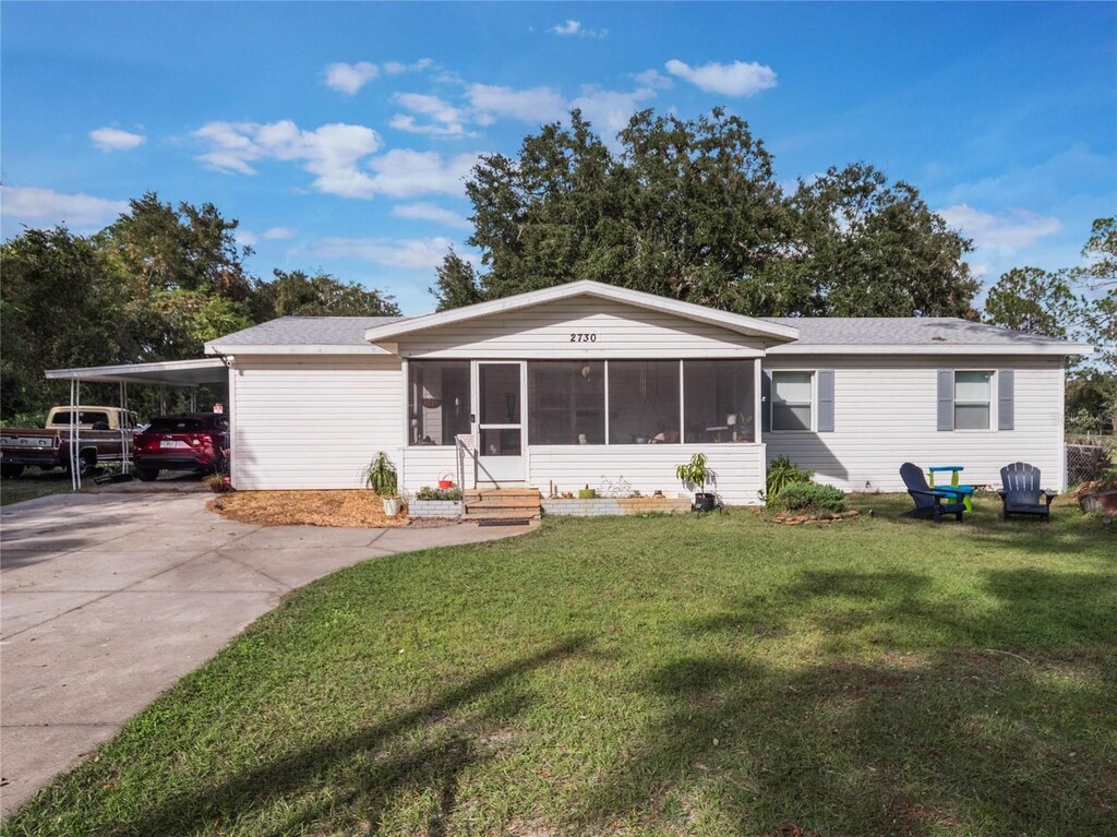 view of front of property with a front yard, a sunroom, and a carport