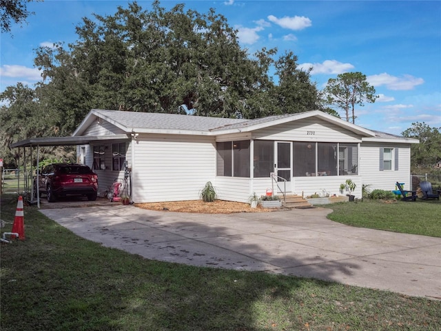 view of front of property with a front lawn, a sunroom, and a carport