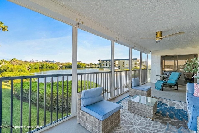 sunroom with ceiling fan and a water view