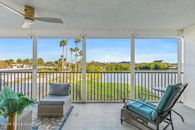 sunroom featuring ceiling fan and a water view