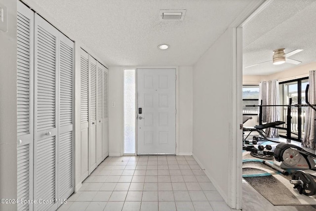 tiled foyer with a textured ceiling and ceiling fan