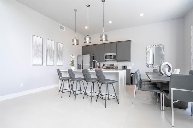 kitchen with hanging light fixtures, a center island with sink, sink, a breakfast bar, and appliances with stainless steel finishes