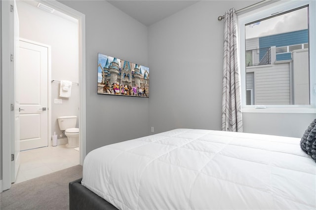 bedroom featuring connected bathroom and light colored carpet